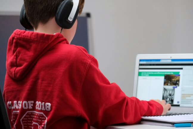 Boy wearing headphones using a laptop