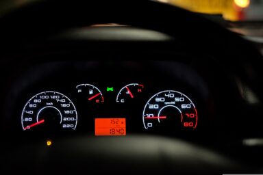 Close-up of an illuminated car dashboard with speedometer and warning lights