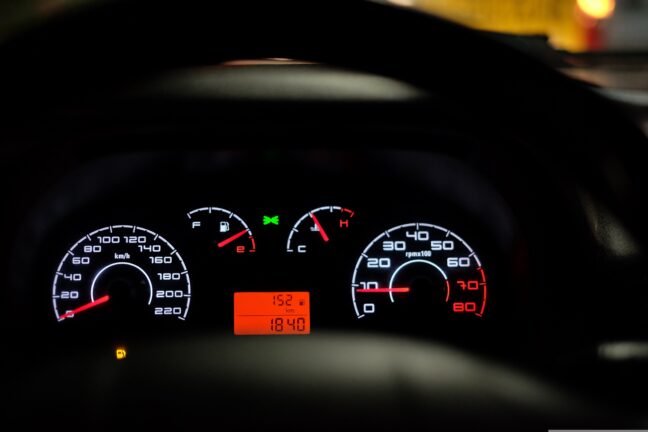 Close-up of an illuminated car dashboard with speedometer and warning lights