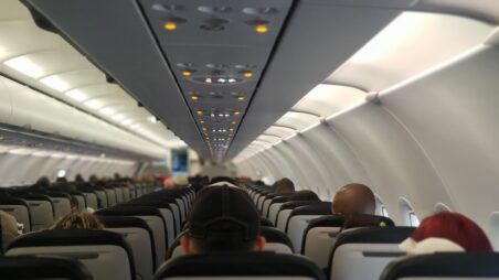 View from behind of airline passengers seated in an aircraft cabin