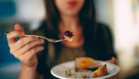 Close-up of a young woman eating food with a fork