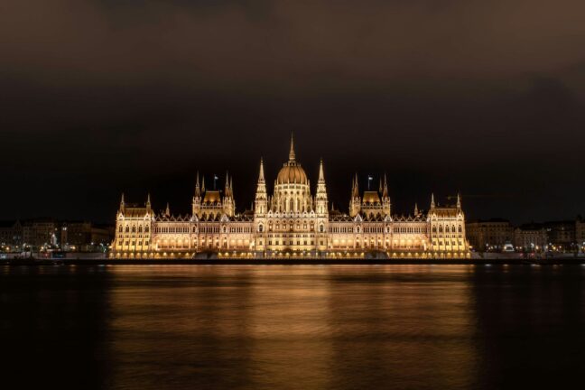 The Hungarian Parliament building illuminated at night, reflected in the Danube.