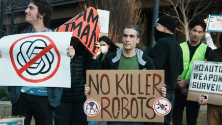 Demonstrators hold signs protesting the use of AI and autonomous weapons
