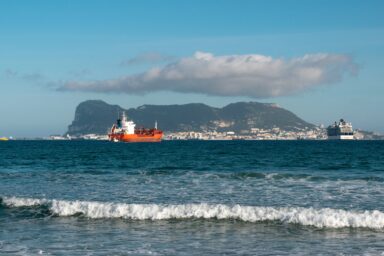 A tanker ship anchored near the Rock of Gibraltar, with a cruise ship and the town visible in the background