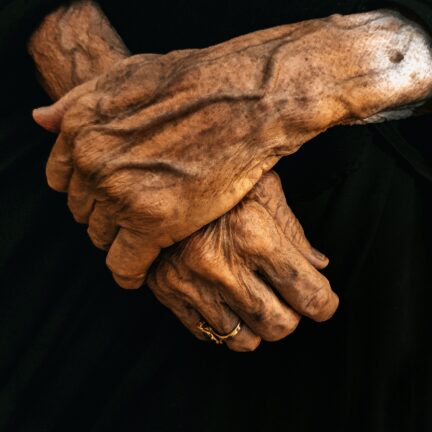 Close-up of an elderly person's clasped hands in dramatic light