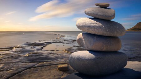 Balanced pebble cairn on a beach with the sea in the background.