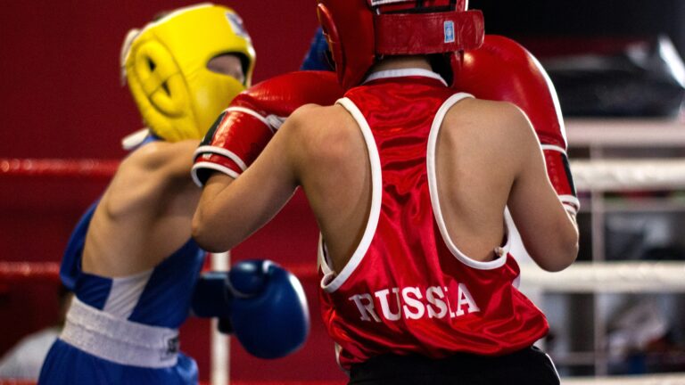 Two boxers compete in a match, one wearing a jersey with "RUSSIA" written on it