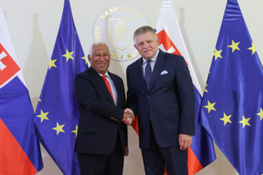 António Costa and Robert Fico shake hands in front of Slovak and EU flags at the Government Office in Bratislava