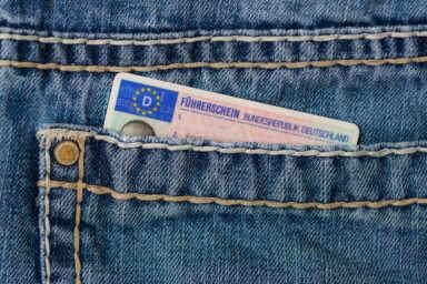 Plastic driving licence card sticking out of a jeans pocket