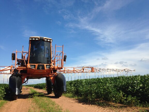 A tractor spraying pesticides on a crop field.