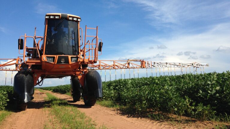 A tractor spraying pesticides on a crop field.