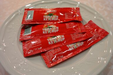 Small ketchup packets lying on a plate.