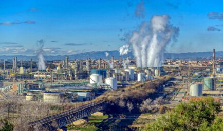 An oil refinery near Reus, Catalonia, with steam rising from its towers against a clear blue sky