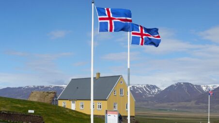 A house with Icelandic flags flying on flagpoles in front