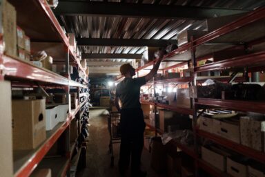Warehouse worker reaching for a shelf in a dimly lit storage facility