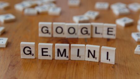 Scrabble tiles spelling out the words 'Google' and 'Gemini' on a wooden table