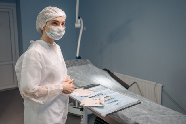 A woman in medical scrubs standing beside a tray of surgical instruments