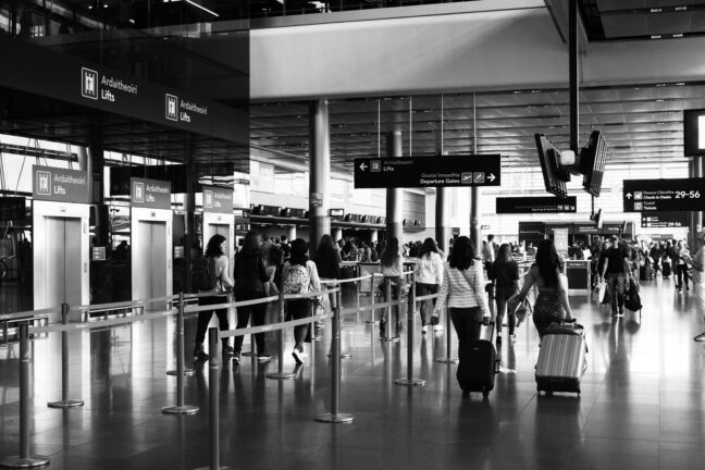 Travellers queuing with luggage at an airport departure hall