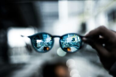 Close-up of sunglasses reflecting a city skyline