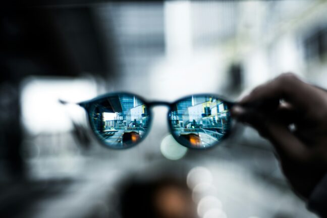 Close-up of sunglasses reflecting a city skyline