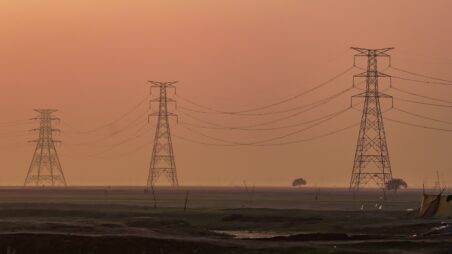Power lines stretching across a hazy sunset landscape