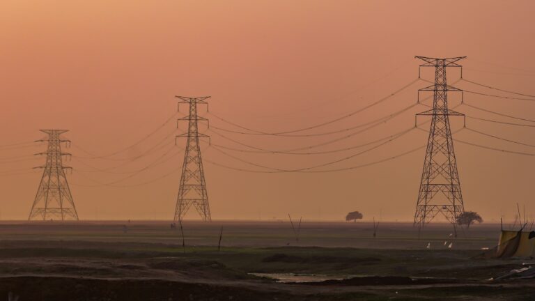 Power lines stretching across a hazy sunset landscape