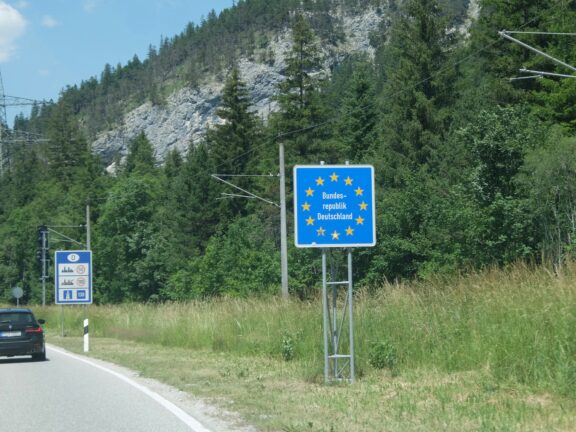 oad sign marking the border crossing into Germany, with an EU-style blue sign reading "Bundesrepublik Deutschland"