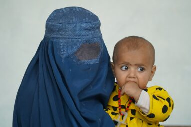 Woman wearing a niqab holding a baby.