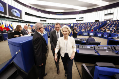 Ursula von der Leyen walking through the European Parliament chamber in Strasbourg, accompanied by two officials, ahead of her State of the Union address.