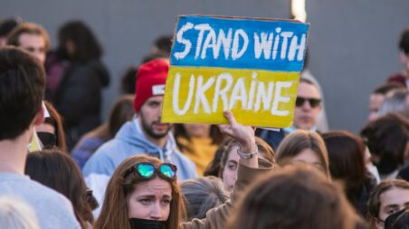Woman holding a “Stand with Ukraine” sign at a demonstration