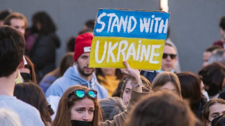 Woman holding a “Stand with Ukraine” sign at a demonstration
