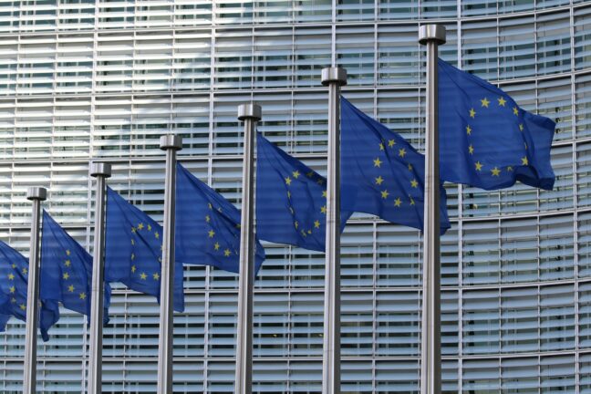 Row of European Union flags outside an EU institution building in Brussels