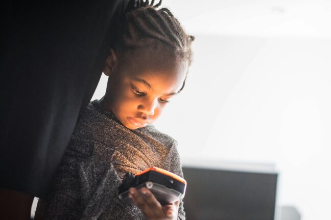 A young child looking down at a smartphone screen