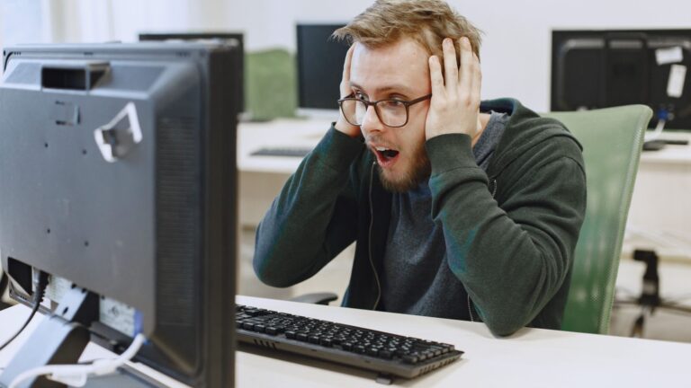 Employee reacting with shock while looking at a computer screen in an office