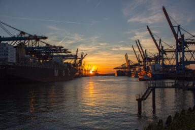 Container ships and cranes at a port at sunset