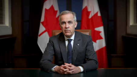 Mark Carney, Prime Minister of Canada, seated at a desk with Canadian flags behind him.