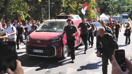 Car carrying Ratko Mladić’s coffin and Serbian flag, accompanied by men in military uniforms