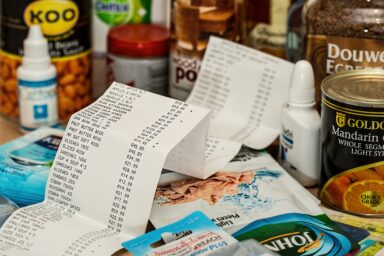 Shopping receipts spread across a kitchen counter surrounded by grocery items