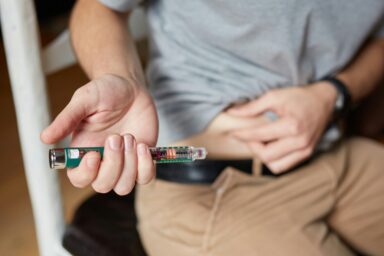 A hand holding out an insulin pen