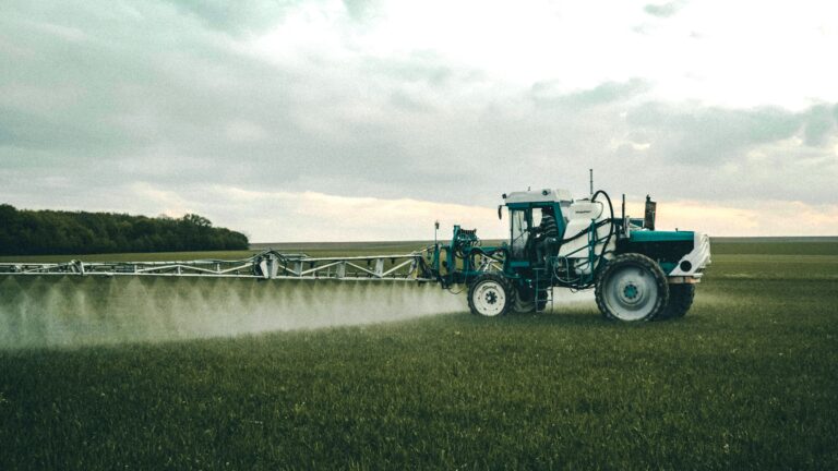 Tractor spraying pesticides on a crop field