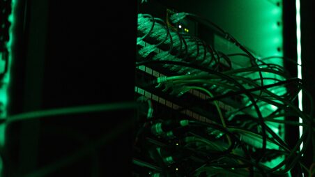 Network cables plugged into a server rack under green light