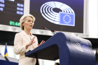 Ursula von der Leyen speaking at a lectern in the European Parliament plenary chamber
