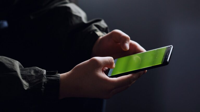 Hands holding a smartphone in a dimly lit room