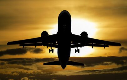 Silhouette of a passenger plane flying against an orange sunset sky