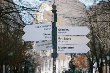 Signpost in Belgrade with arrows in Cyrillic, Greek and Latin script pointing to districts of Skopje, Athens, Moscow, Vienna, Brussels and Paris
