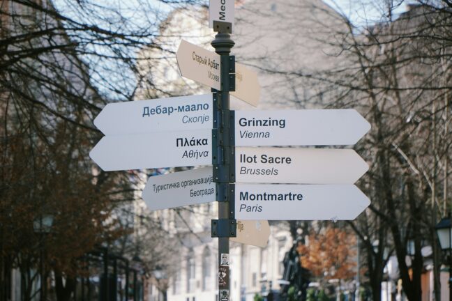 Signpost in Belgrade with arrows in Cyrillic, Greek and Latin script pointing to districts of Skopje, Athens, Moscow, Vienna, Brussels and Paris