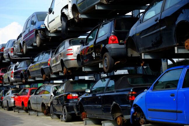 Used cars stacked on top of each other in metal racks at a scrapyard