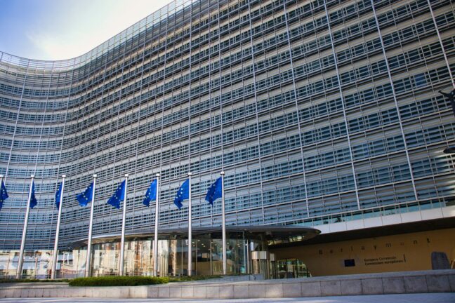 Berlaymont building, the European Commission headquarters in Brussels, with a row of EU flags in front