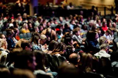 Audience in a conference hall, several people taking notes