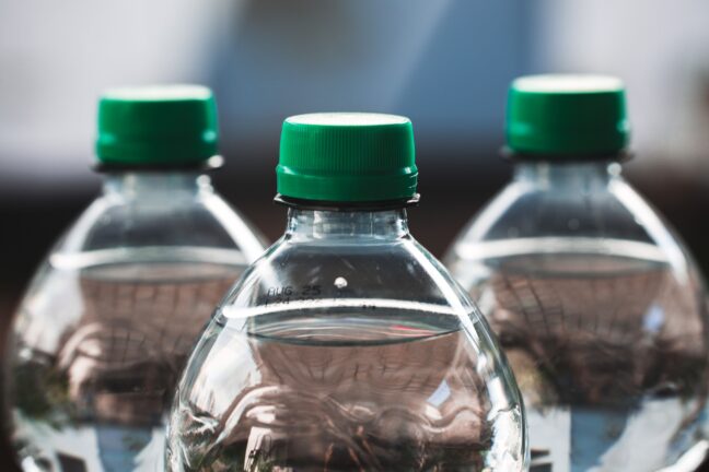Three plastic water bottles with green caps, close-up